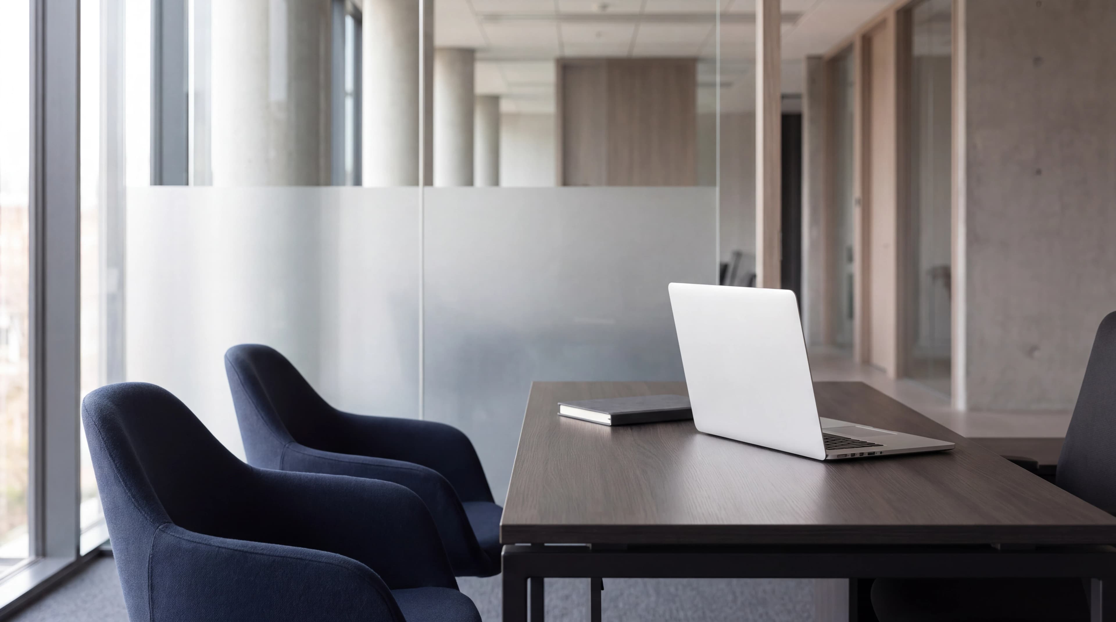 A quiet meeting space with a laptop and notebook on a desk